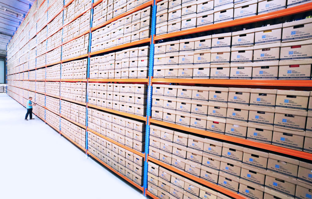 A photo of a warehouse with organized products in boxes stacked on a shelf showing warehouse optimization is important